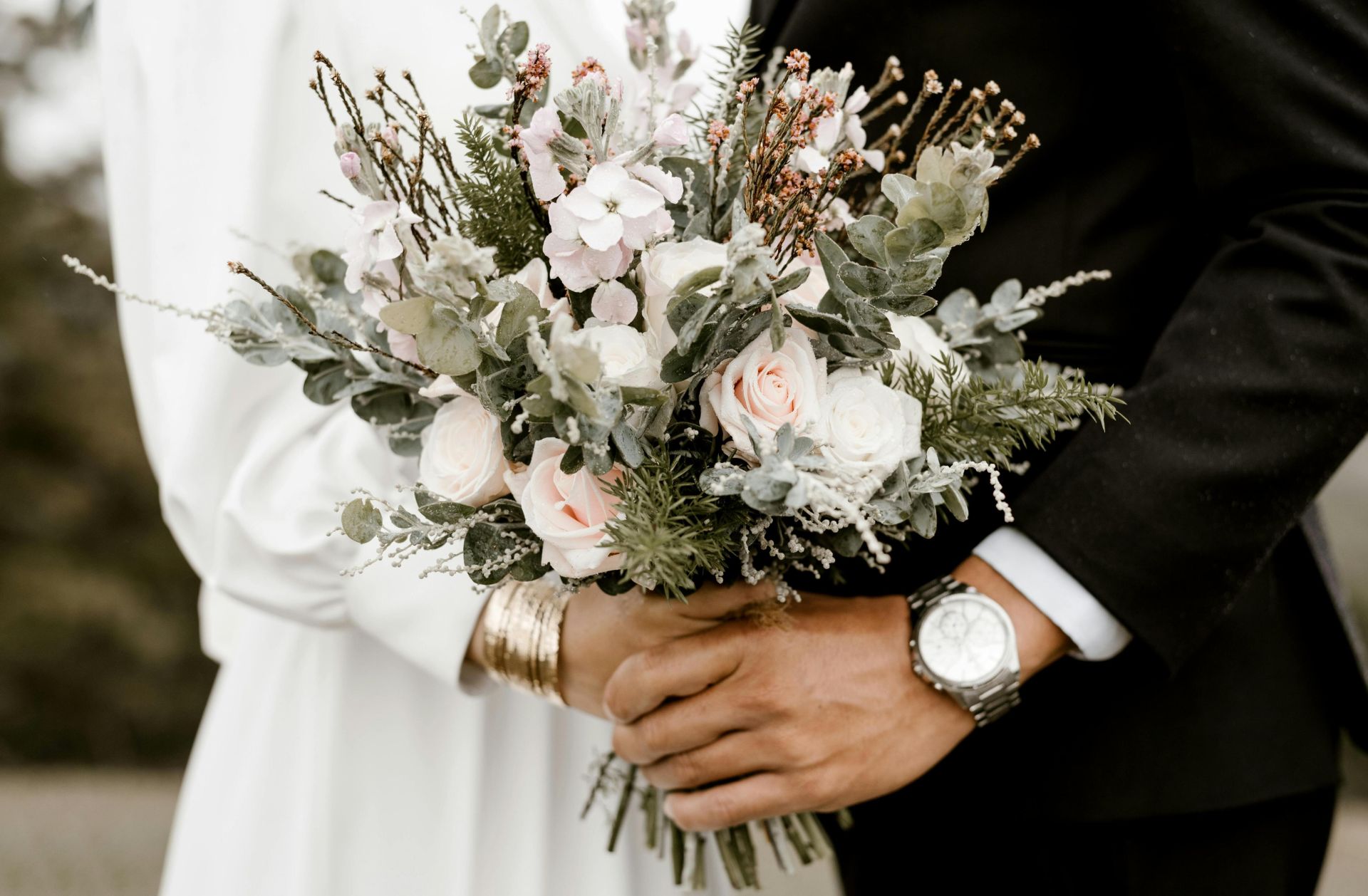 Close-up of a wedding bouquet held by bride and groom, showcasing romance and elegance.