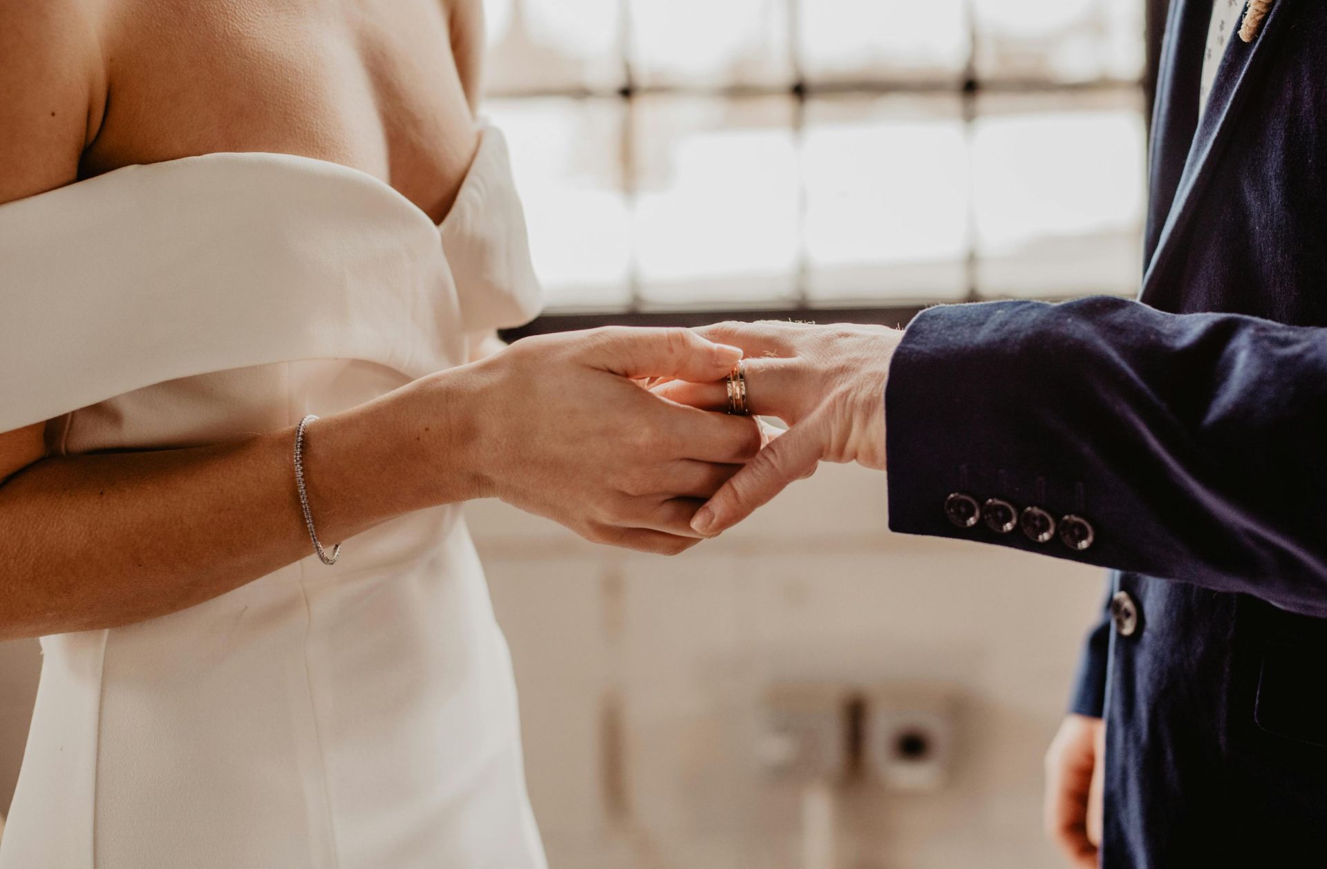 Close-up of wedding couple exchanging rings during a ceremony indoors.